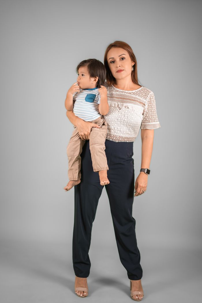 contact-img A fashionable mother holding her young child against a gray backdrop, showcasing modern parenting.